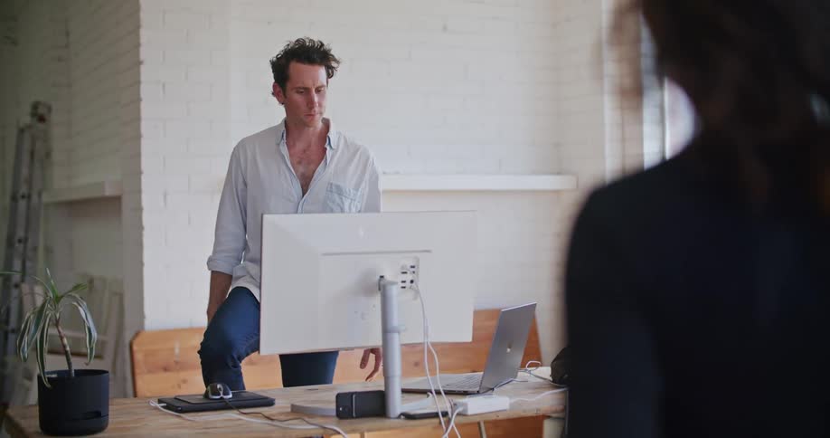 Man in white shirt gives instructions to another man wearing a futuristic motion capture black suit