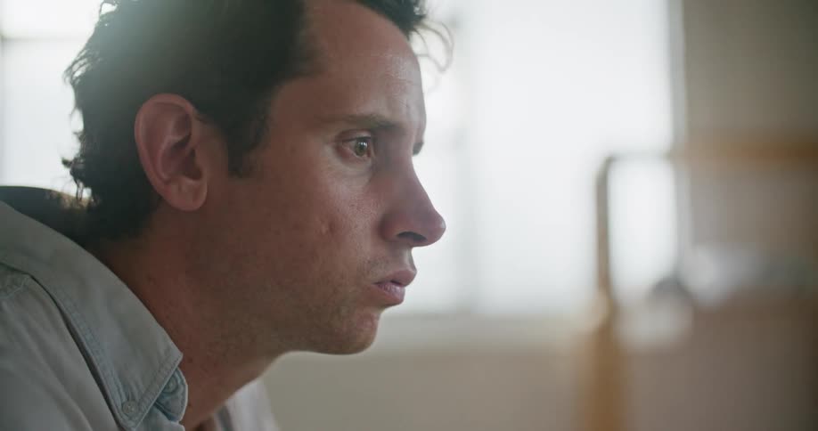 A man is looking at a laptop computer with an image of a hand on the screen