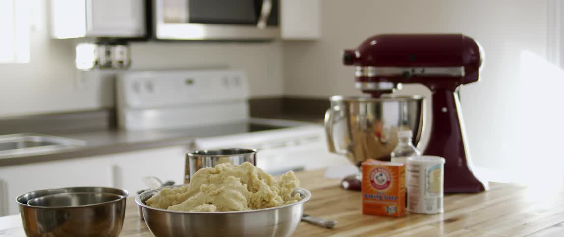 A mixing bowl turns behind a bowl of dough