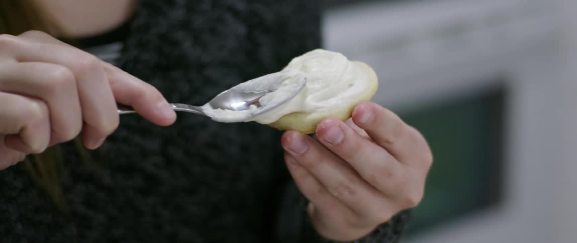 Creamy substance being applied to a cookie with a spoon