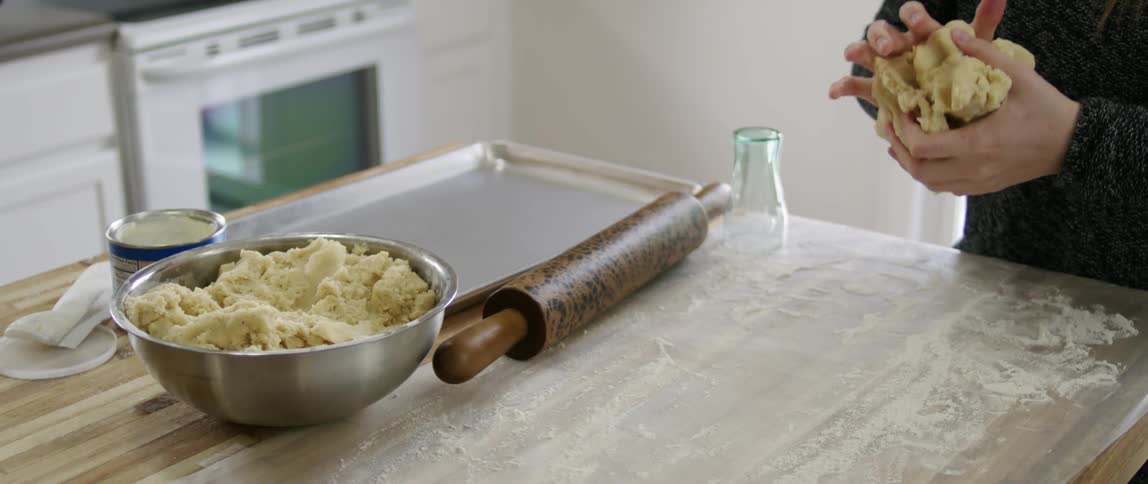 A person picks up dough from a bowl