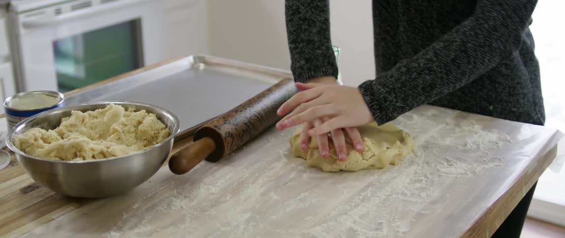 Person flattening cookie dough with their hands