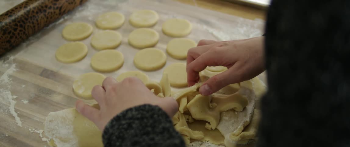 Woman removing excess cookie dough from her cookies