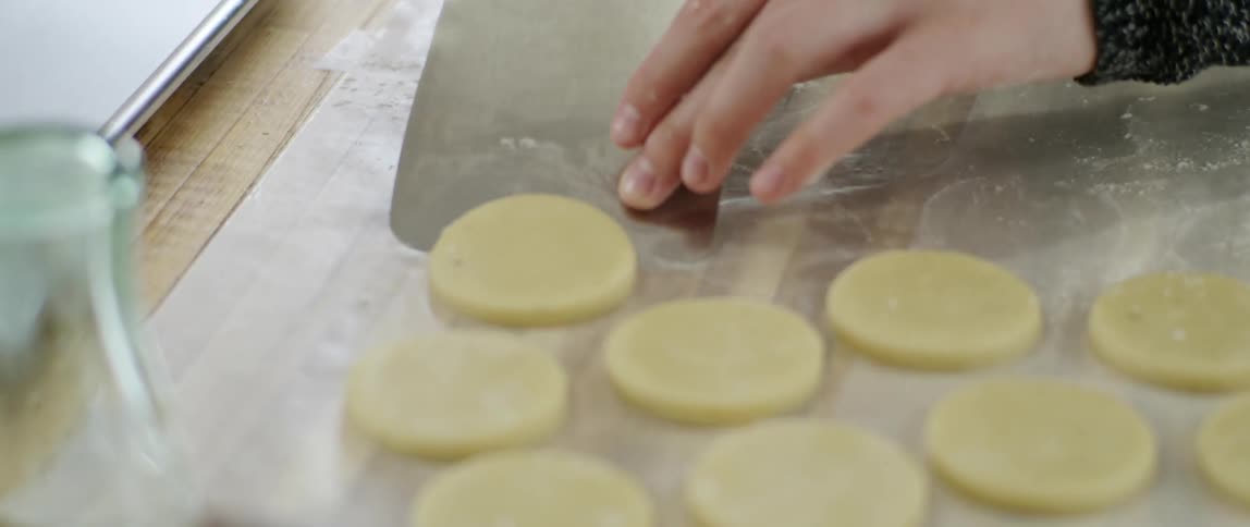 Small pieces of dough are being placed on a pan
