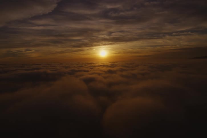The sun is setting above the clouds