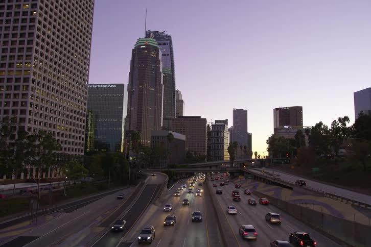 Aerial view of cars driving on highways near a city is displayed