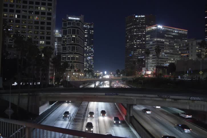 Cars are driving on highways through a downtown city