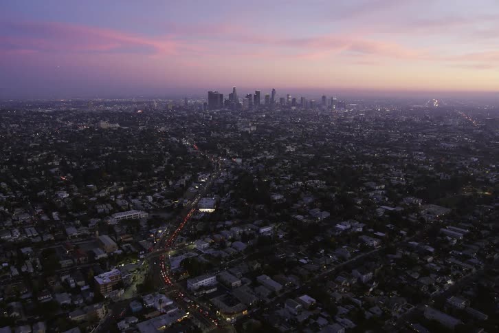 An aerial view of a city with cars driving on streets and buildings spread out