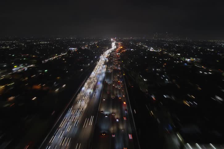 Traffic flows along highway through city at night