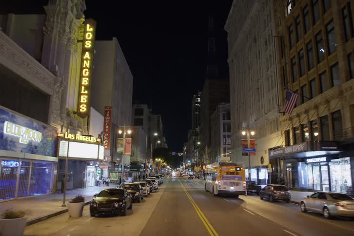 Cars are driving in a downtown city at night