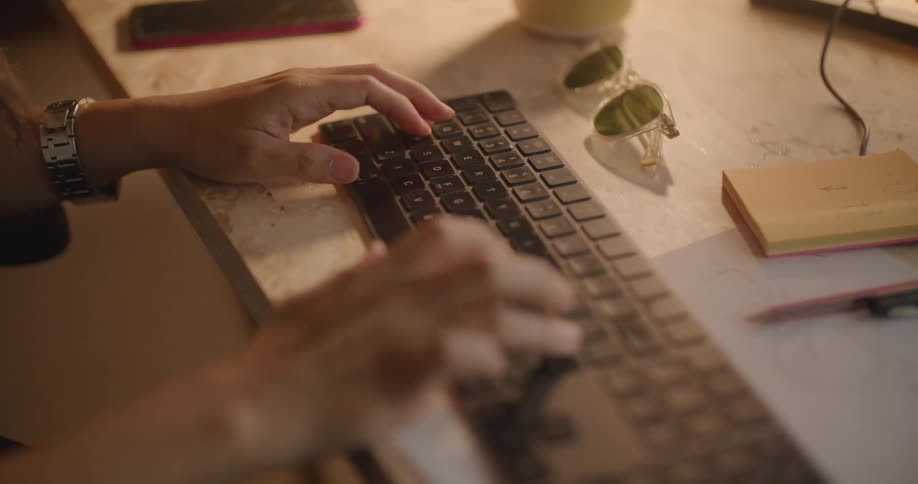 Woman with gray wristwatch types on computer keyboard
