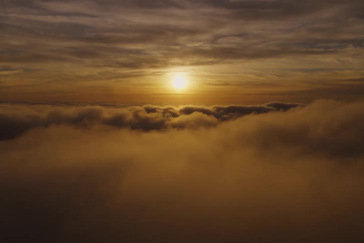 The sun shining above clouds