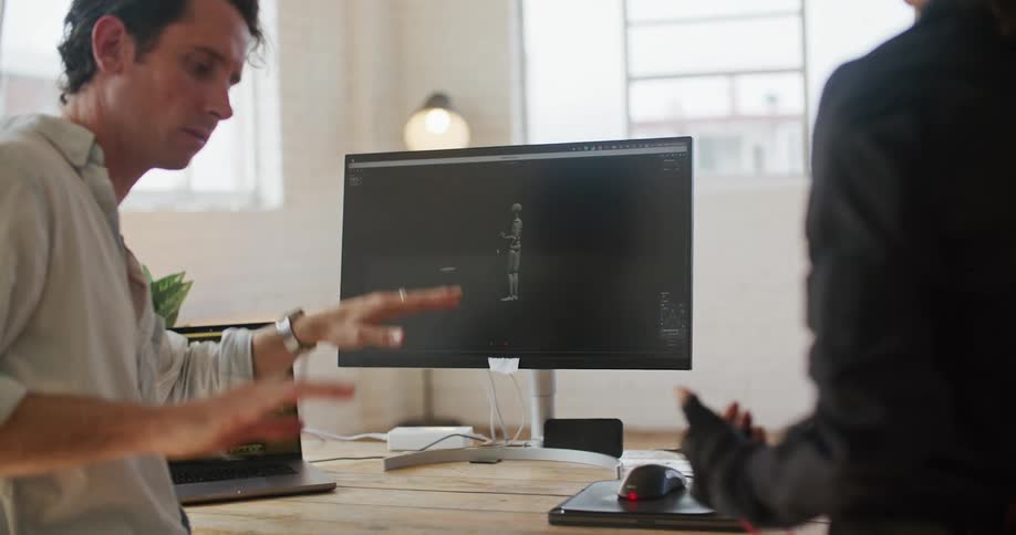 Two men are talking together and looking at a computer