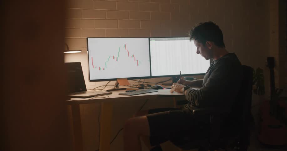 A man is checking stock prices and writing things down