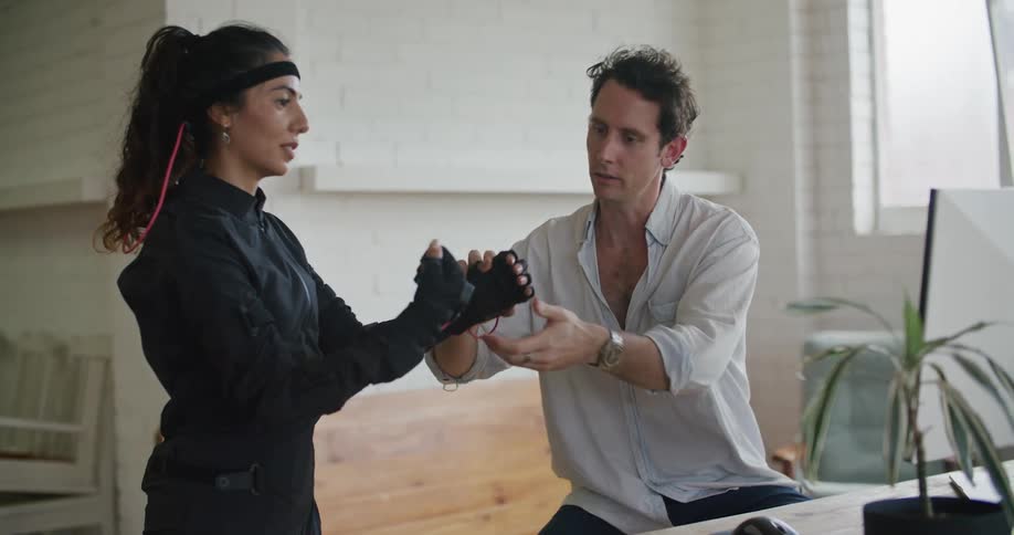 Man and woman smile and talk as he checks sensors on the motion capture suit she is wearing