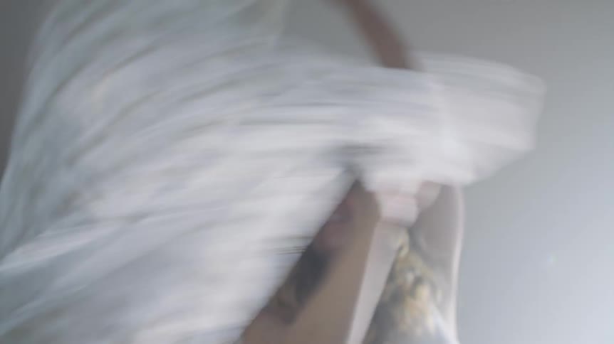 A woman at home waves a sheet in the air