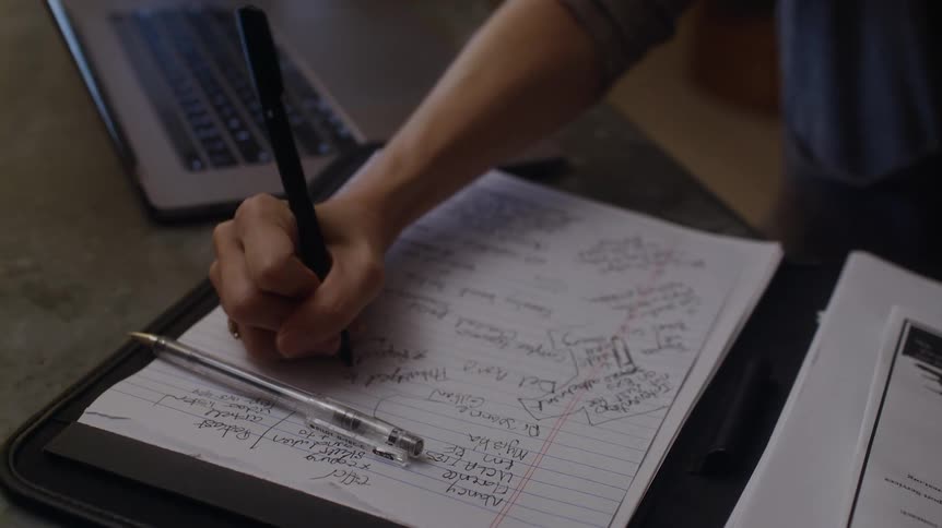 A student writes quickly while taking notes in class