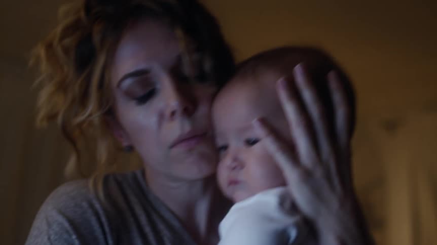 Worried mother holding her baby checking his temperature and kissing his cheek
