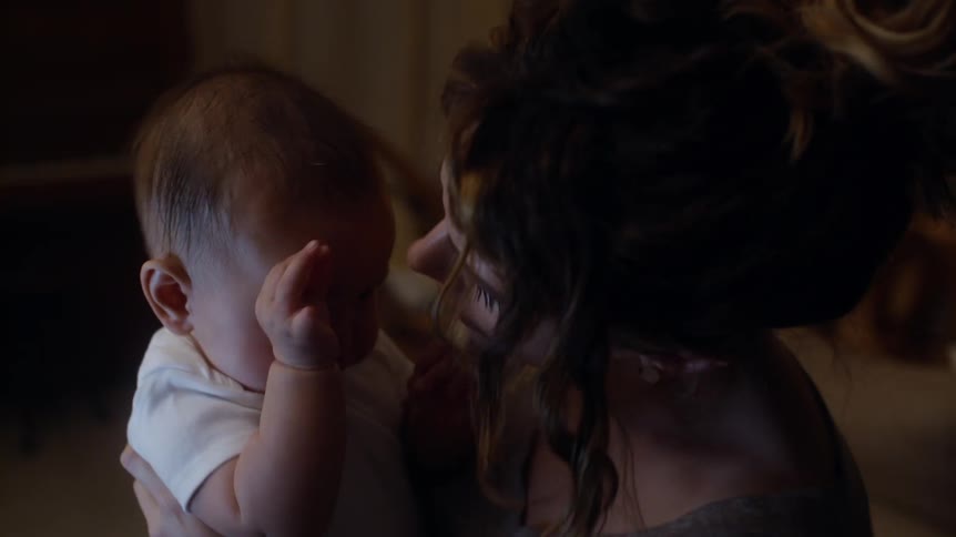 Woman standing in the living room holding her baby while it cries and then kissing it in the cheek