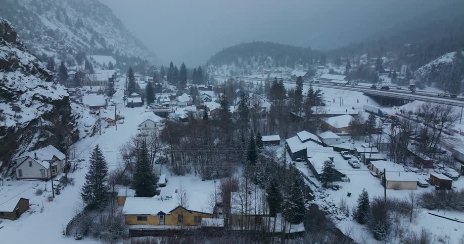 Cars are driving near a small town in winter