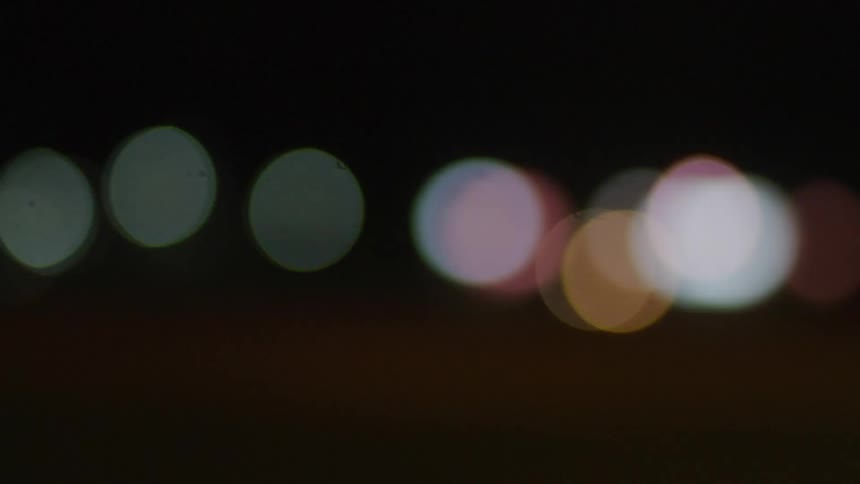 Various circular colored lights flash in the darkness
