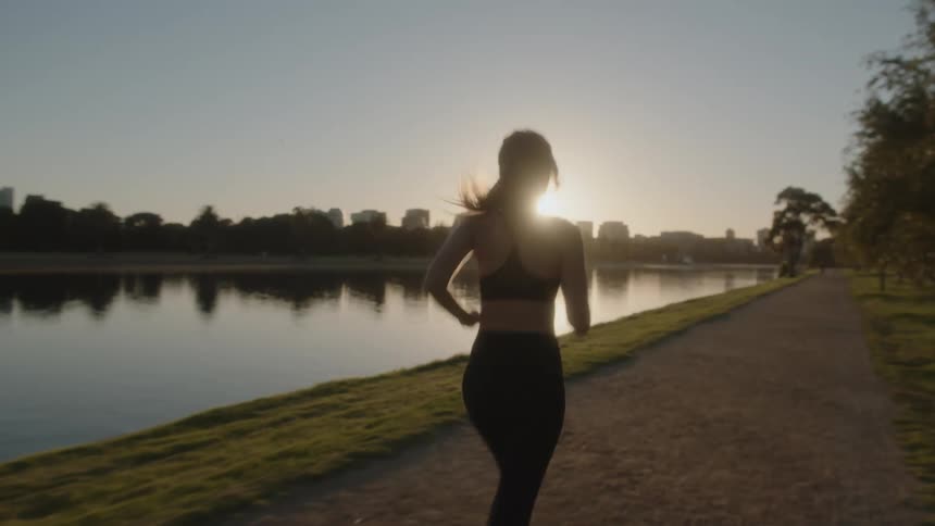 A woman is jogging outdoors on the coast at dusk