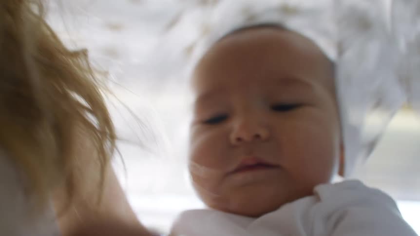 A baby reaches around crying
