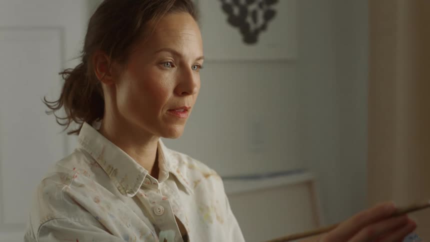 Female holding a paint pallet painting on a canvas frame