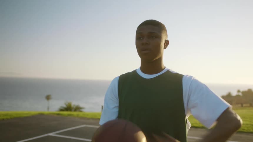 A man throws layups on a basketball court along the coast