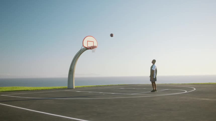 A man is playing basketball by himself in spring