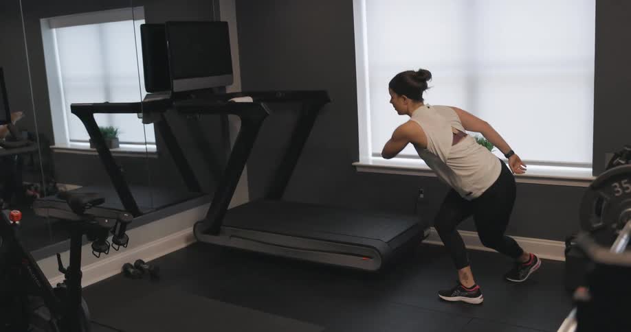 Woman exercising jumping from side to side in front of a mirror at a gym room