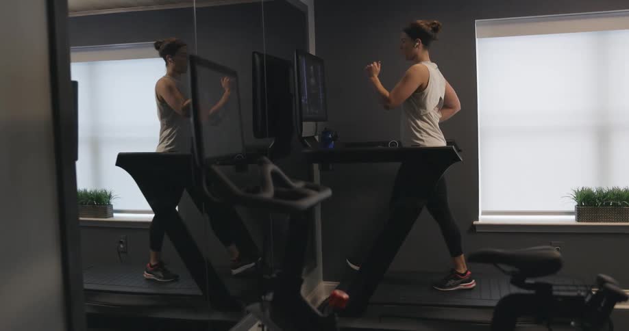 A woman is walking on a treadmill in a gym