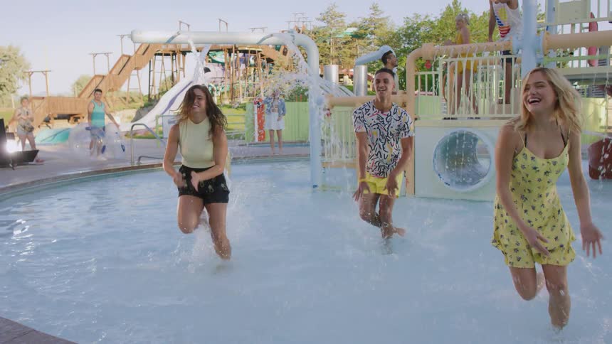 Teenagers dancing at a waterpark as people stand in the background and dance and clap