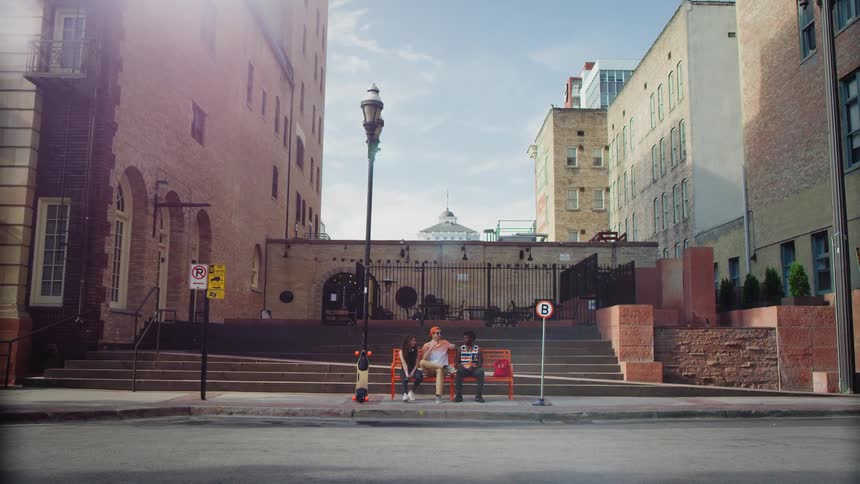 A group of friends sit on a bench downtown
