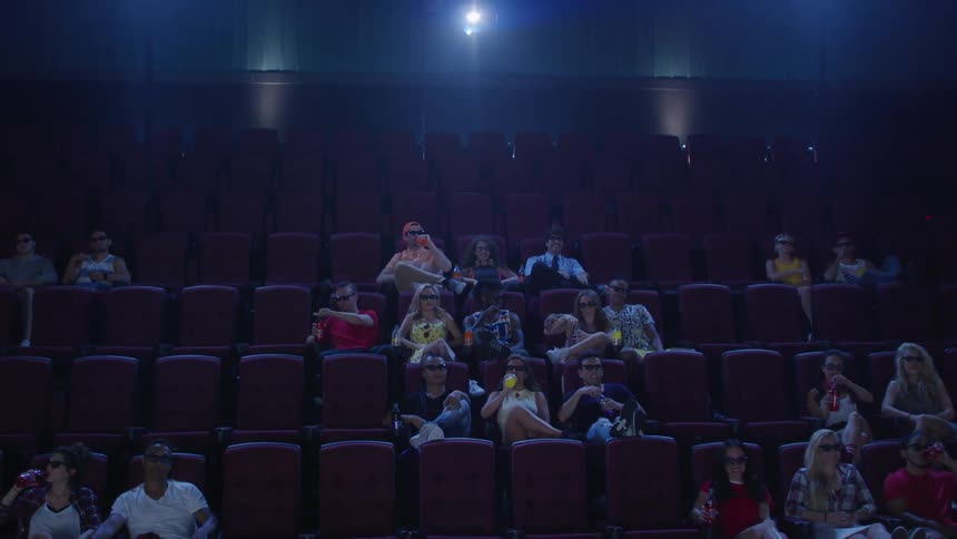 A crowd watch something in a theater