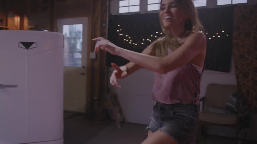 A young woman dances in front of her friends while one of them films from a smartphone