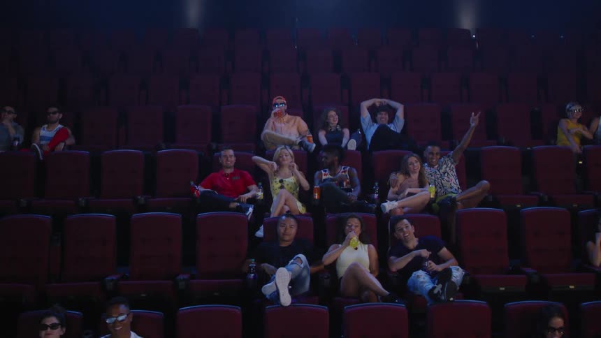 People cheer while watching something in the theater