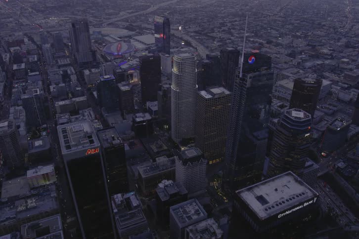 Heavy traffic flows along multilane highway passing downtown and heading toward fog covered buildings nearing the horizon and the sun