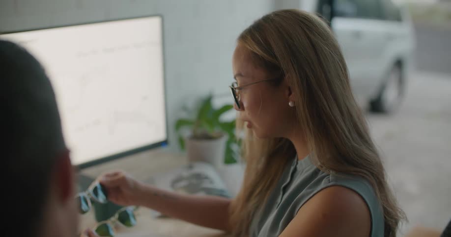 A man and woman are in the office looking at sunglasses
