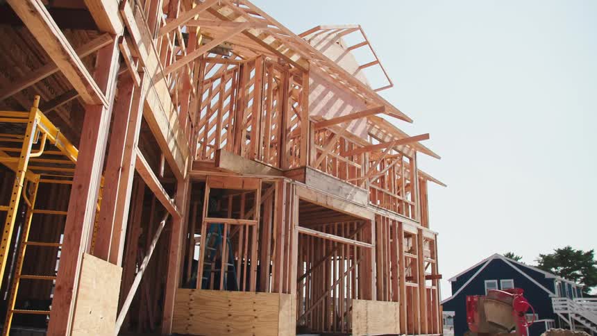 The wood frame of a house is completed in a neighborhood