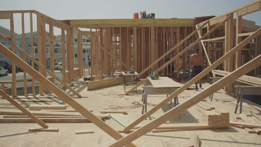 Two construction workers move through houses wooden framework