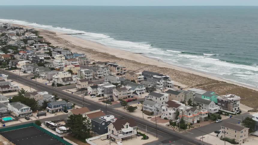 Aerial of beach houses on the coast while a cars drives by