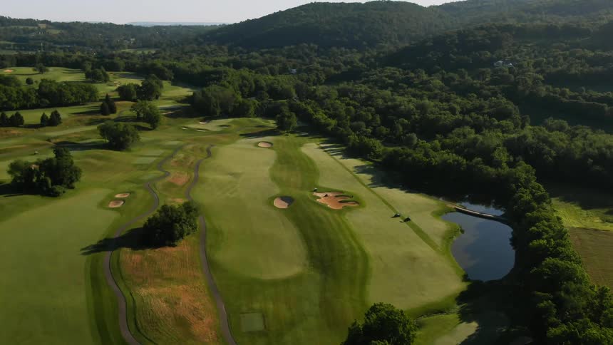Aerial drone shot of a golf course next to a forest