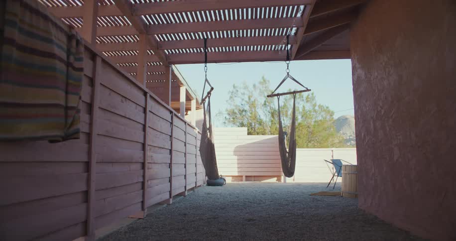 Hammocks swaying in the wind hanging under a patio cover
