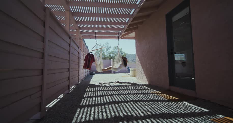 Woman relaxing on a hammock under a patio cover on a breezy day
