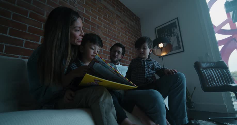 A woman reads to her sons on the couch