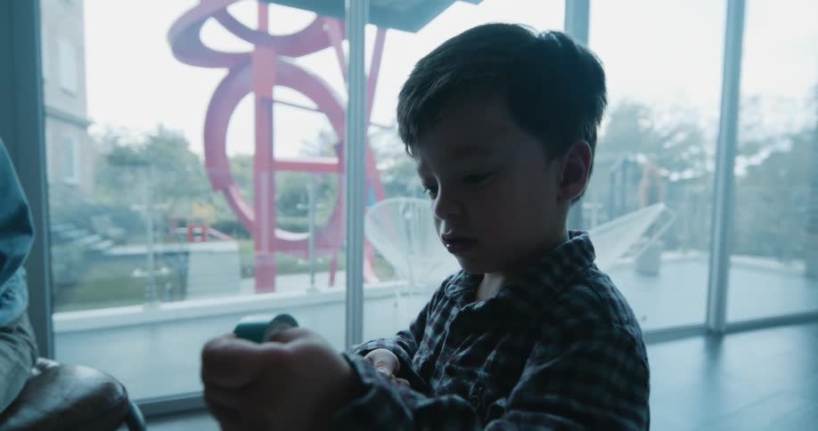 A boy unravels a roll of green tape and hands it to his mom
