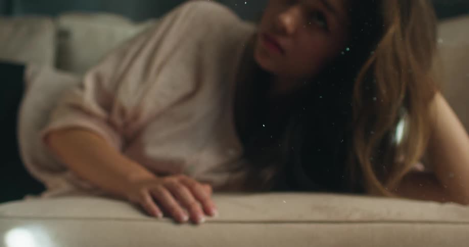 Teenager girl lying in the couch watching the dust particles fall down