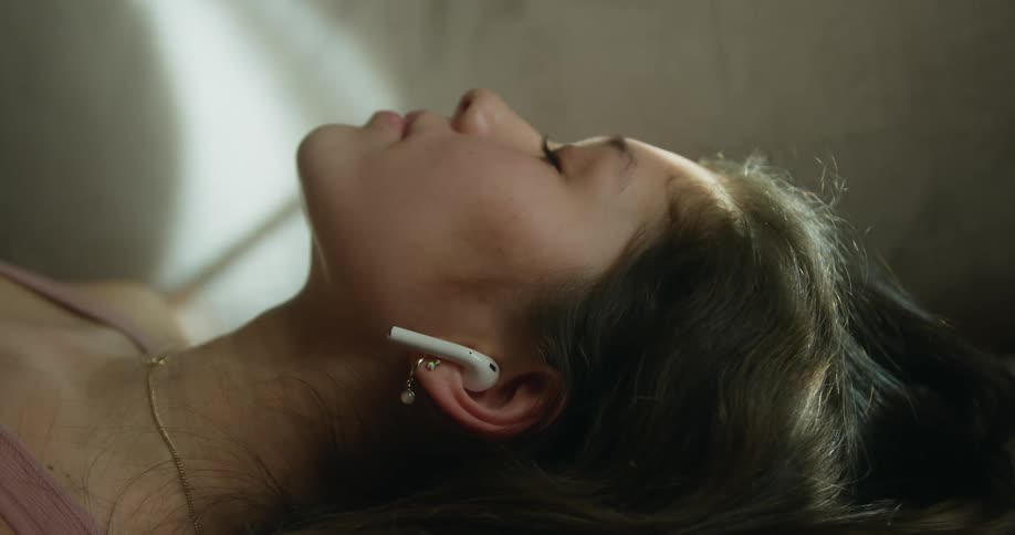 Woman wearing a wireless earphone lying down in the floor