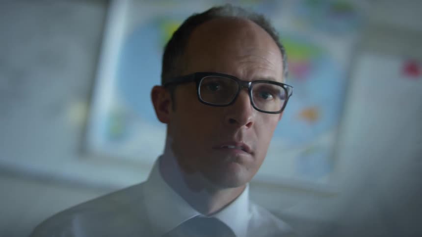 Man with glasses shirt and tie stares at camera